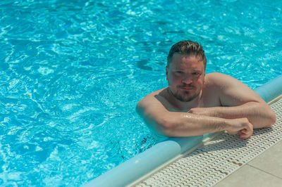 Portrait of shirtless man swimming in pool