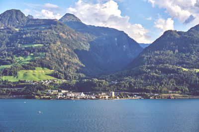 Scenic view of sea by mountains against sky