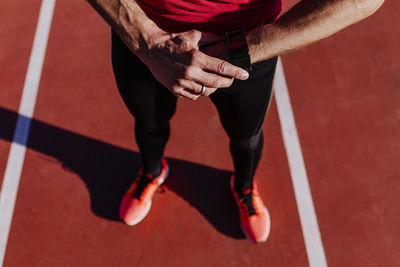 Low section of athlete wearing smart watch on sports track