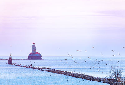 View of lighthouse by sea against sky