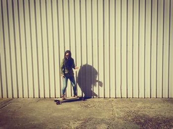 Full length of man skateboarding against wall