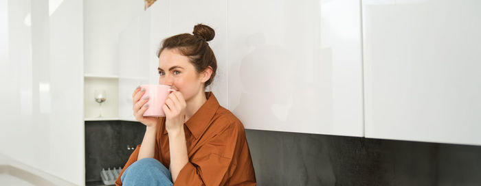 Side view of young woman standing against wall