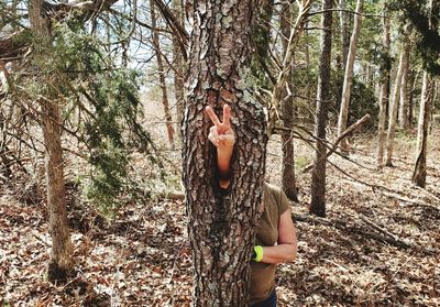 Woman by tree trunk in forest