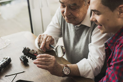 Senior man and grandson with toy train at home