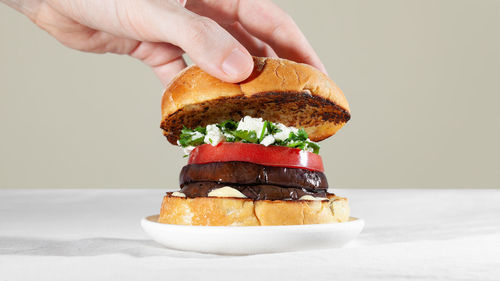 Midsection of hand holding ice cream against white background