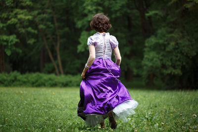 Woman in dress running away towards forest, fear concept