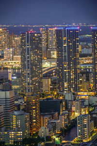 Illuminated modern buildings in city against sky at night