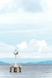 Lighthouse by sea against sky