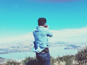 Rear view of man standing against blue sky