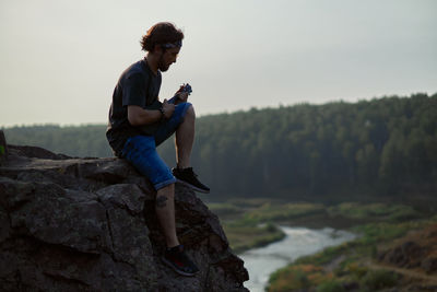 Side view of man photographing on rock