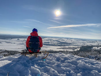 Rear view of person on snowcapped mountain against sky