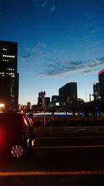 Cars on road by buildings against sky in city at night