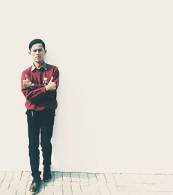 Portrait of young man standing against wall