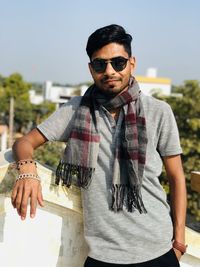 Portrait of young man wearing sunglasses standing against sky