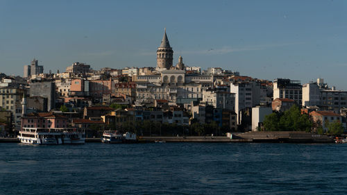 Sea by buildings in city against sky