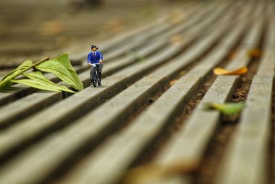 Optical illusion of figurine riding bicycle on footpath