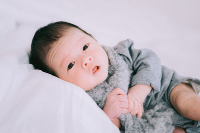 Portrait of cute baby lying on bed