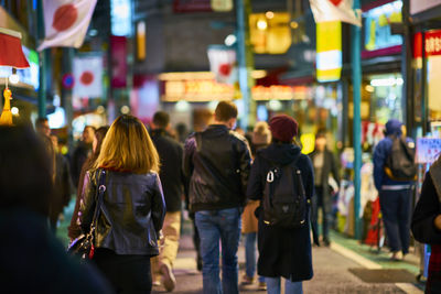 People walking on city street amidst shops at night