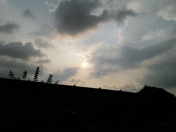 Silhouette of trees against cloudy sky