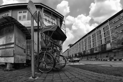 Bicycles on street by buildings against sky