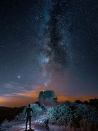 Rear view of man standing against sky at night