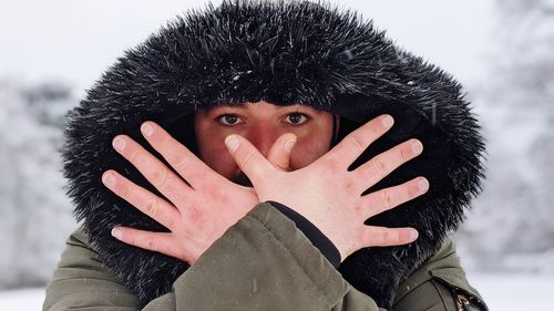 Portrait of man covering face with snow