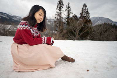 Woman sitting on snow covered land