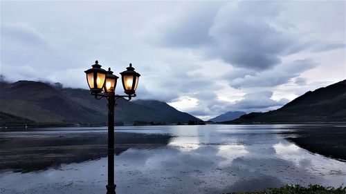 Street light by lake against sky during winter