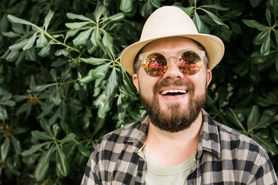 Portrait of young man wearing sunglasses against plants
