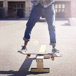 Low section of man skateboarding on road