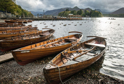Fishing boats moored at lake against sky