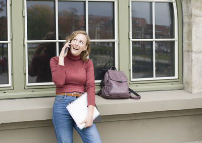 A young girl back to school, stands with a backpack and talks on the phone