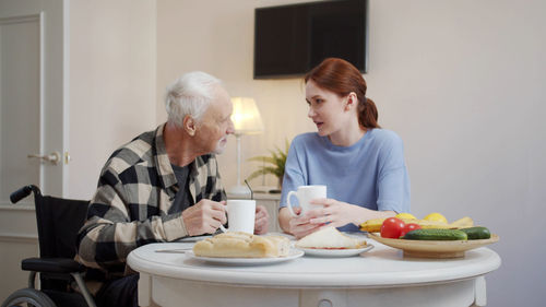 Smiling nurse and man eating food at nursing home