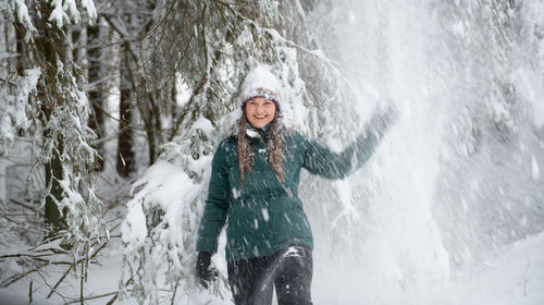 Portrait of young woman standing against waterfall