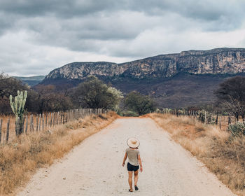 Rear view of man walking on dirt road
