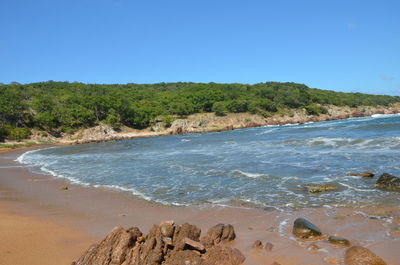 Scenic view of beach against clear blue sky