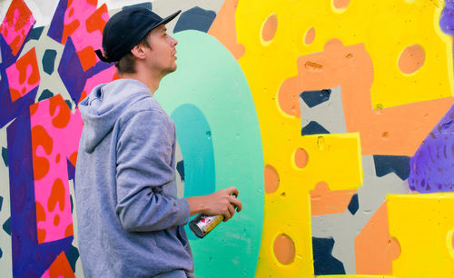Young man spray painting wall