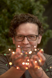 Close-up portrait of smiling man holding lighting equipment outdoors