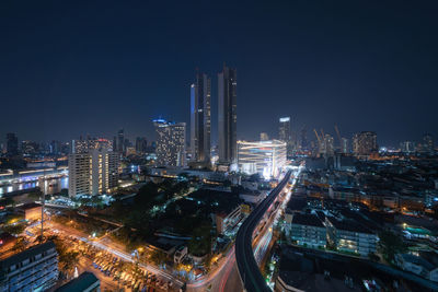 Illuminated modern buildings in city against sky at night