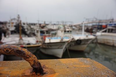 Close-up of boats moored at harbor against sky