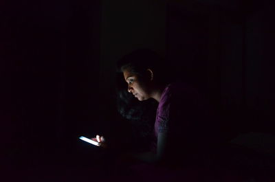 Teenage girl using mobile phone in dark room