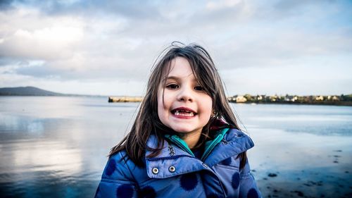 Portrait of smiling young woman against sky