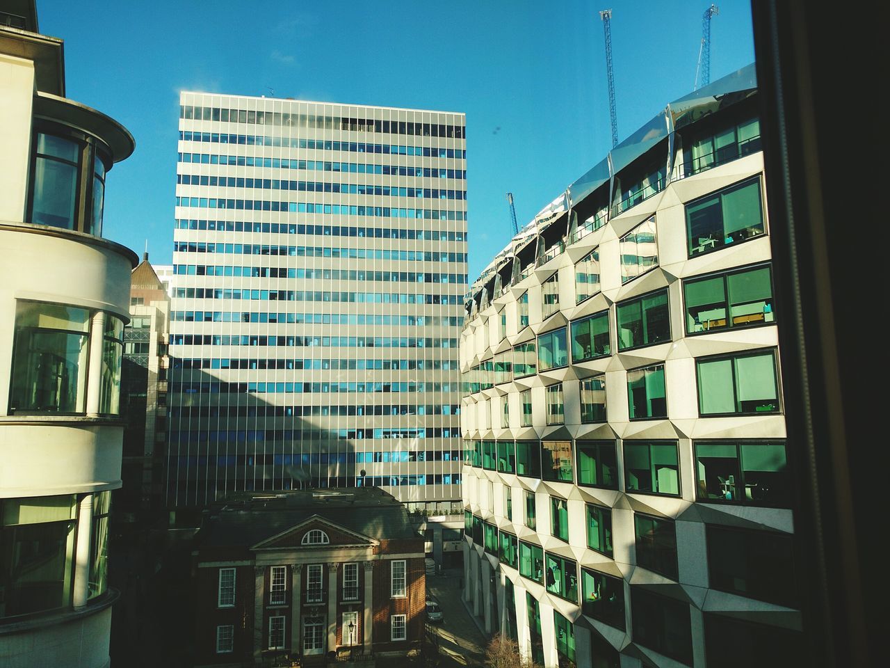 building exterior, architecture, built structure, window, city, building, clear sky, residential building, low angle view, residential structure, glass - material, modern, office building, sky, reflection, blue, apartment, day, sunlight, no people