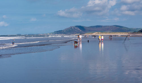 People enjoying at beach against sky