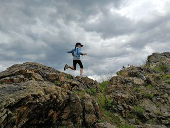 Man standing on rock against sky