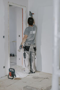 A young builder is plastering a doorway.
