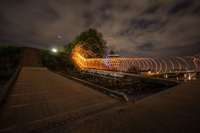 Illuminated railroad tracks against sky at night