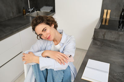 Side view of young woman standing by wall