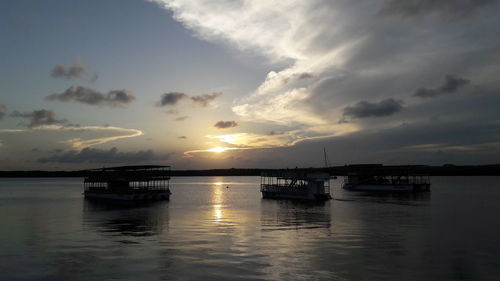 Silhouette boats moored on sea against sky during sunset