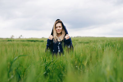 Young woman standing on field against sky